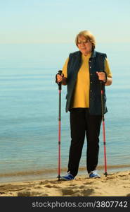 active mature lifestyle. senior nordic walking on a sandy beach sea shore.