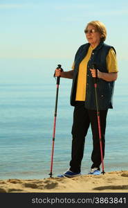 active mature lifestyle. senior nordic walking on a sandy beach sea shore.