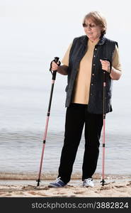 active mature lifestyle. senior nordic walking on a sandy beach sea shore.