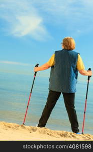 active mature lifestyle. senior nordic walking on a sandy beach sea shore.