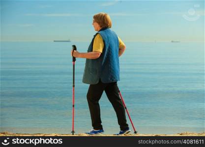 active mature lifestyle. senior nordic walking on a sandy beach sea shore.