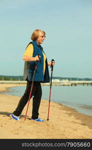 active mature lifestyle. senior nordic walking on a sandy beach sea shore.