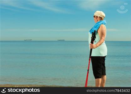 active mature lifestyle. senior nordic walking on a sandy beach sea shore.