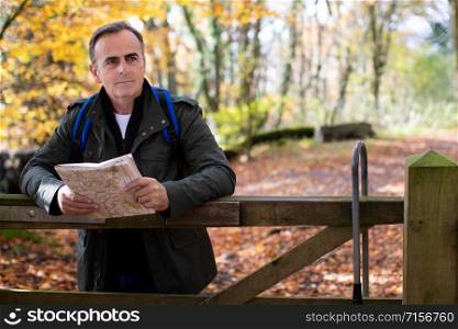 Active Mature Man With Map Walking Through Autumn Woodland
