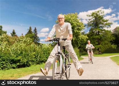 active old age, people and lifestyle concept - happy senior couple riding bicycles at summer park. happy senior couple riding bicycles at summer park