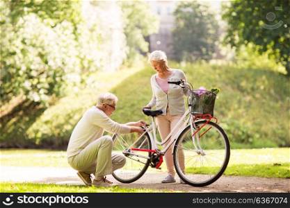 active old age, people and lifestyle concept - happy senior couple with fixie bicycle at summer city park. happy senior couple with bicycle at summer park