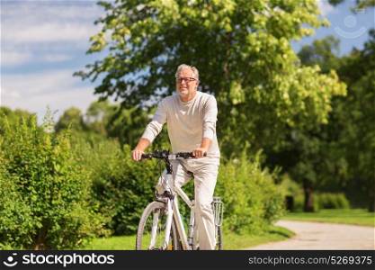 active old age, people and lifestyle concept - happy senior man riding fixie bicycle at summer park. happy senior man riding bicycle at summer park