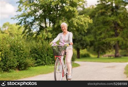 active old age, people and lifestyle concept - happy senior woman riding fixie bicycle at summer park. happy senior woman riding bicycle at summer park