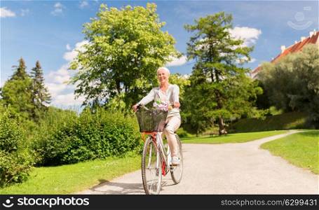 active old age, people and lifestyle concept - happy senior woman riding fixie bicycle at summer park. happy senior woman riding bicycle at summer park