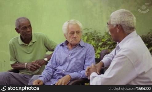 Active retired elderly people and free time, group of happy senior african american and caucasian male friends talking and sitting on bench in park. Sequence