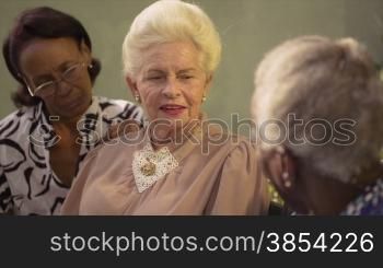 Active retired elderly women and free time, group of happy senior african american and caucasian female friends talking and sitting on bench in park. Sequence