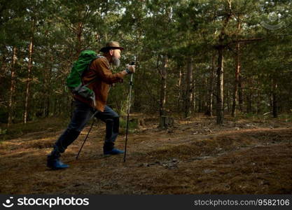 Active retired man hiking in forest. Senior male tourist having workout walk on nature. Relax outside, trekking and adventure for retirement on weekend vacation. Active retired man hiking having workout walk on nature