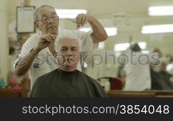 Active retired old people, man getting an haircut by senior barber in old fashion barber&acute;s shop or male beauty parlor