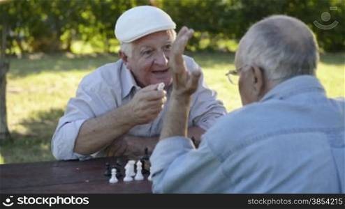 Active retired people, old friends and free time, two seniors having fun and playing chess game at park. Sequence of closeup and medium shot