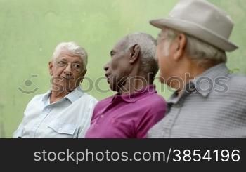 Active retirement and senior people, group of three elderly male friends talking and laughing on bench in public park. Sequence