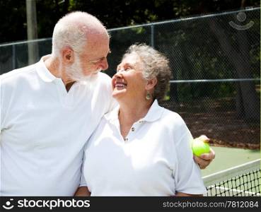 Active senior couple gets romantic on the tennis courts.