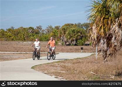 Active senior couple riding their bicycles on a beautiful sunny day.