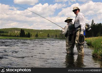Active senior male gives fly-fishing lesson to senior female in active retirement.