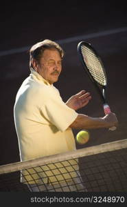 Active senior man in his 70s is playing tennis.