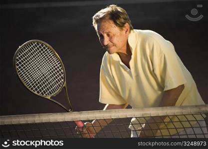 Active senior man in his 70s is playing tennis.