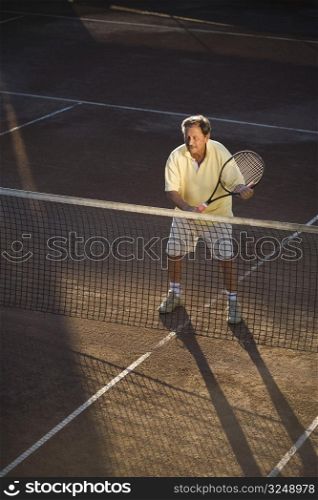 Active senior man in his 70s playing tennis.