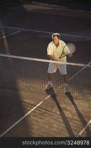Active senior man in his 70s playing tennis.
