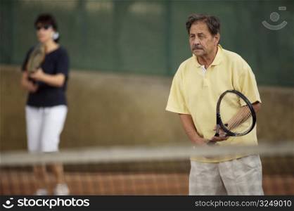 Active senior man in his 70s plays tennis.