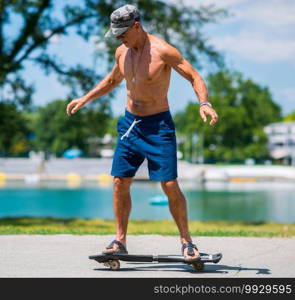 Active senior man riding a snakeboard by the lake