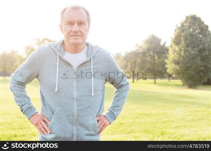 Active senior man standing with hands on hips in park