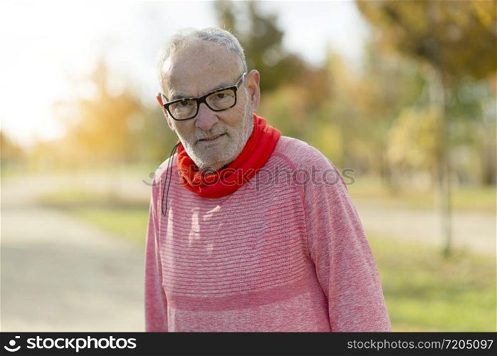 Active senior runner in red sweatshirt in nature resting.