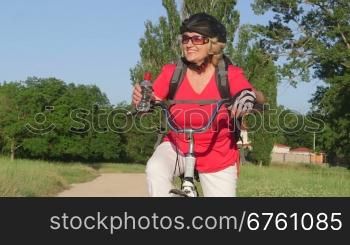 Active senior woman cyclist on bicycle looking away smiling