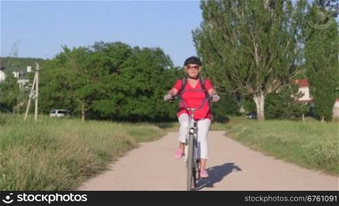 Active senior woman cyclist riding bicycle in the park