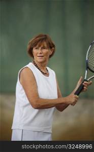 Active senior woman in her 60s plays tennis.