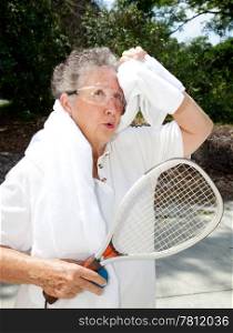 Active senior woman takes a break from racquetball to towel herself off.
