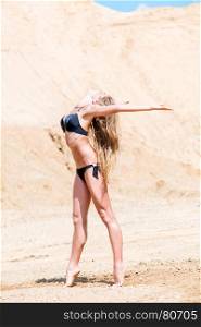 active sportswoman in bikini on sand posing