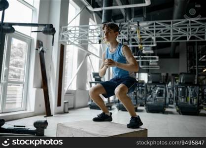 Active teenager boy training at gym. Schoolboy athlete using sports fitness cube equipment for cardio exercise. Active teenager boy training using sports fitness cube