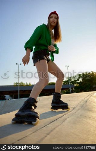 Active teenager girl rollerskater riding at outdoor rollerdrom. Summer recreational activity. Active teenager girl rollerskater riding at outdoor rollerdrom
