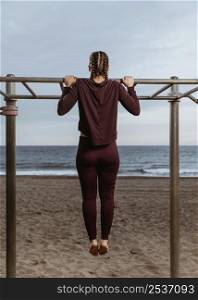 active woman doing fitness exercises outside by beach