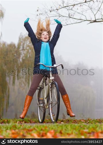 Active woman having fun riding bike in autumn park. Happy carefree active woman having fun riding bike bicycle in fall autumn park. Crazy young girl relaxing. Healthy lifestyle and recreation leisure activity.