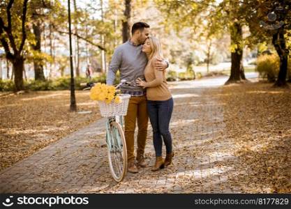 Active young couple enjoying together in riding bicycle at golden autumn park