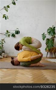 Active young couple resting in child pose while practicing yoga together at home. Family workout. Young couple practicing child yoga pose together