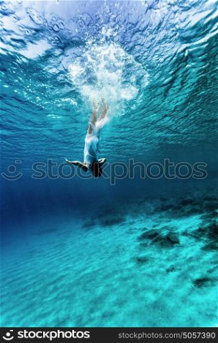 Active young female dancing underwater, enjoying summer vacation in blue transparent water, dive to the bottom of sea, enjoyment and freedom concept