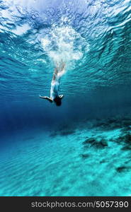 Active young female dancing underwater, enjoying summer vacation in blue transparent water, dive to the bottom of sea, enjoyment and freedom concept