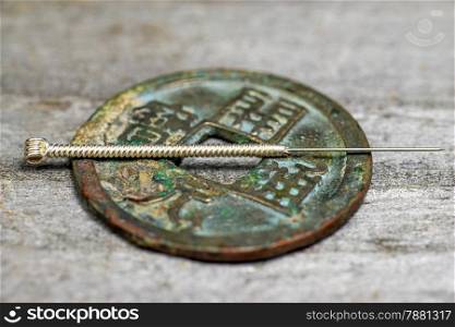 acupuncture needle on antique chinese coin