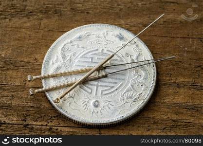 acupuncture needles on chinese coin