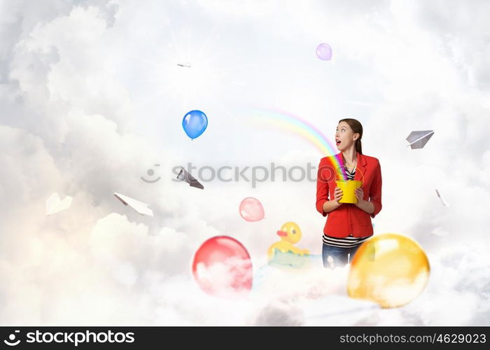 Add color and holiday to your life. Young pretty woman with yellow bucket in hands and colorful balloons flying out