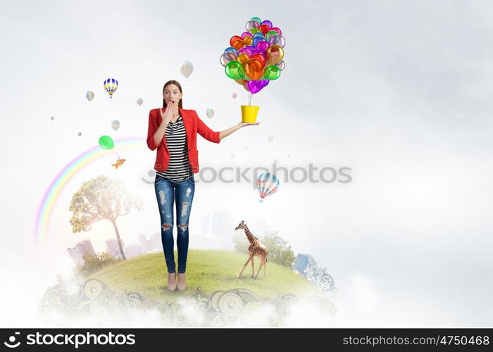 Add color and holiday to your life. Young pretty woman with yellow bucket in hands and colorful balloons flying out