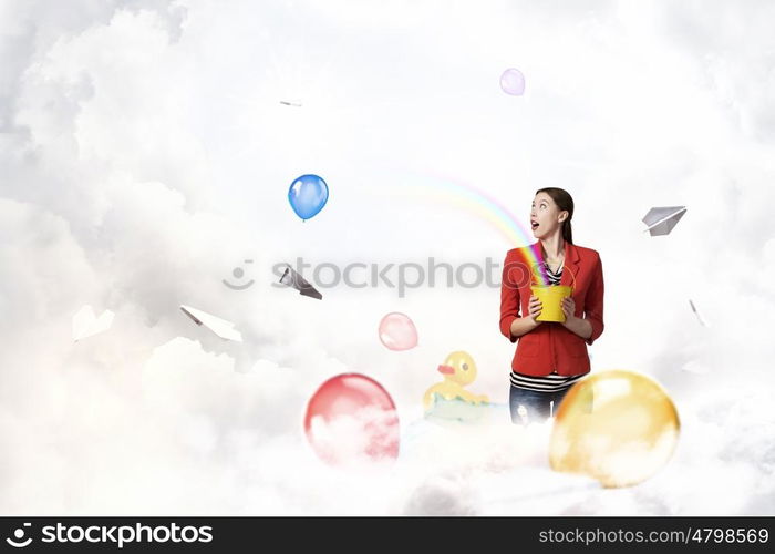 Add color and holiday to your life. Young pretty woman with yellow bucket in hands and colorful balloons flying out