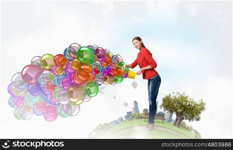 Add color and holiday to your life. Young pretty woman with yellow bucket in hands and colorful balloons flying out