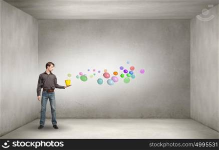 Add some color to your life!. Young man in casual splashing colorful balloons from bucket